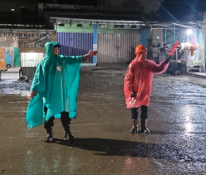 Hujan Mengguyur, Bhabinkamtibmas Desa Lingga Tetap Siaga Atur Lalu Lintas di Jalan Lintas Sumatera
